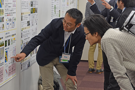 ポスター発表会場(環境動態部門)発表者がポスターを指差し説明する様子