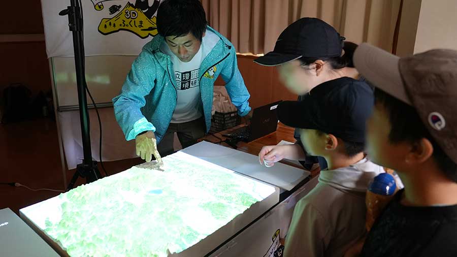 辻主任研究員から説明を聞く来場者
