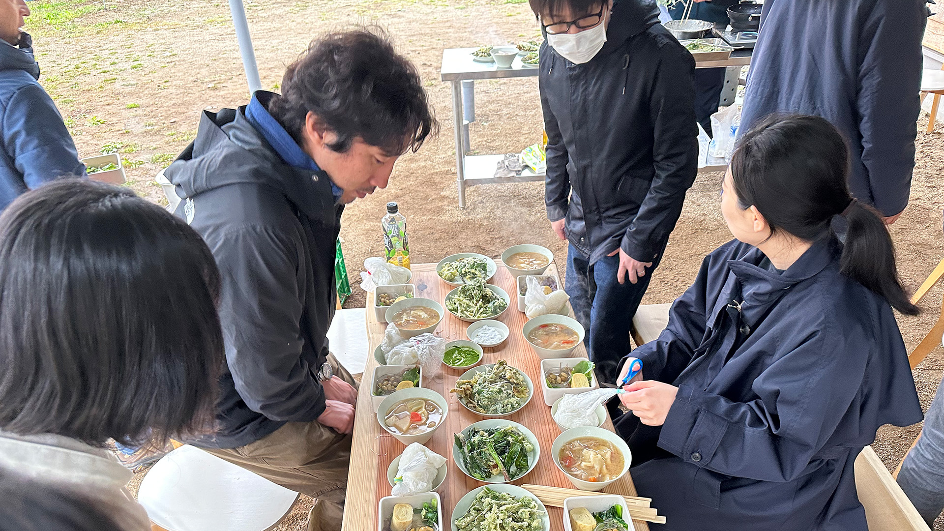 ご飯と“まんがこ”、山の農園で採れた野菜の天ぷらなどが載った食卓を囲む様子