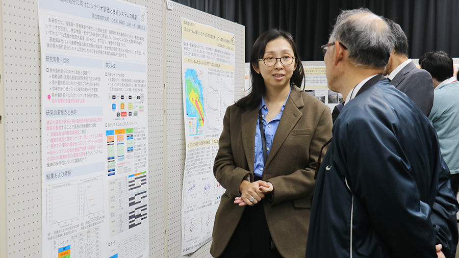 ポスターセッションで来場者に説明する三成研究員