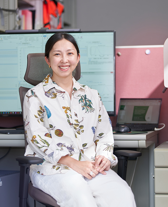 デスクの前で笑顔の三成研究員