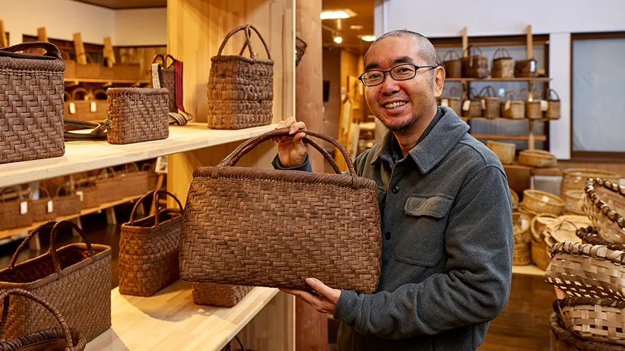 三島町の工芸品である編み組細工を手にもつ中村主任研究員
