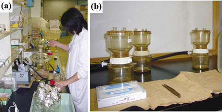 写真２　ろ過の様子　　(a)ガラス繊維ろ紙によるろ過、(b)0.2-mmメンブレンろ紙によるろ過。ろ過器を３個使わないと、帰宅が12時を過ぎてしまう。